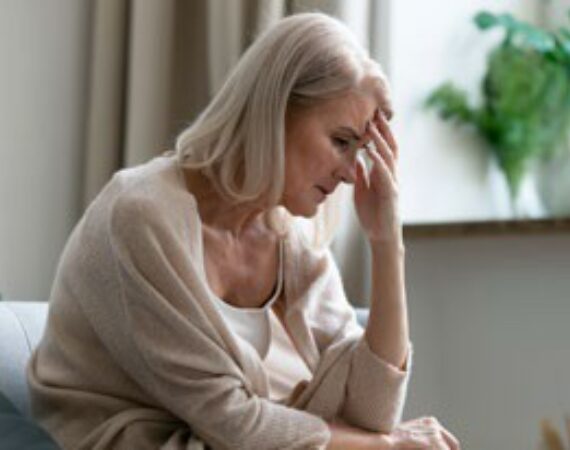 Frau mittleren Alters leidet unter Fatigue und hält sich den Kopf