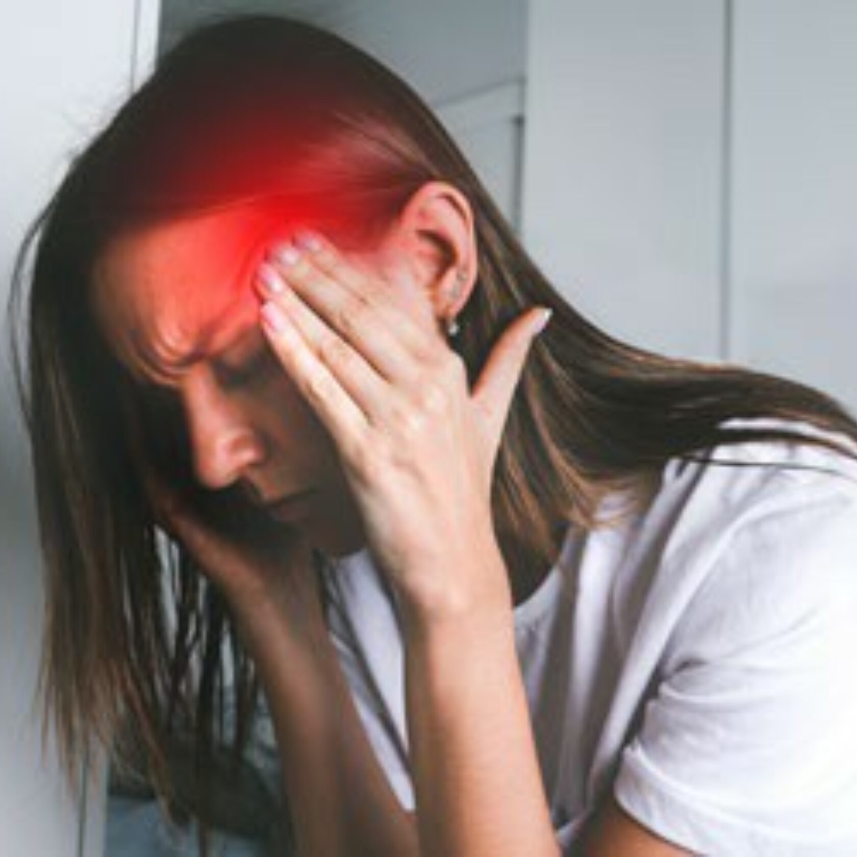 Frau fasst sich an die Schläfen und leidet offensichtlich unter starken Kopfschmerzen
