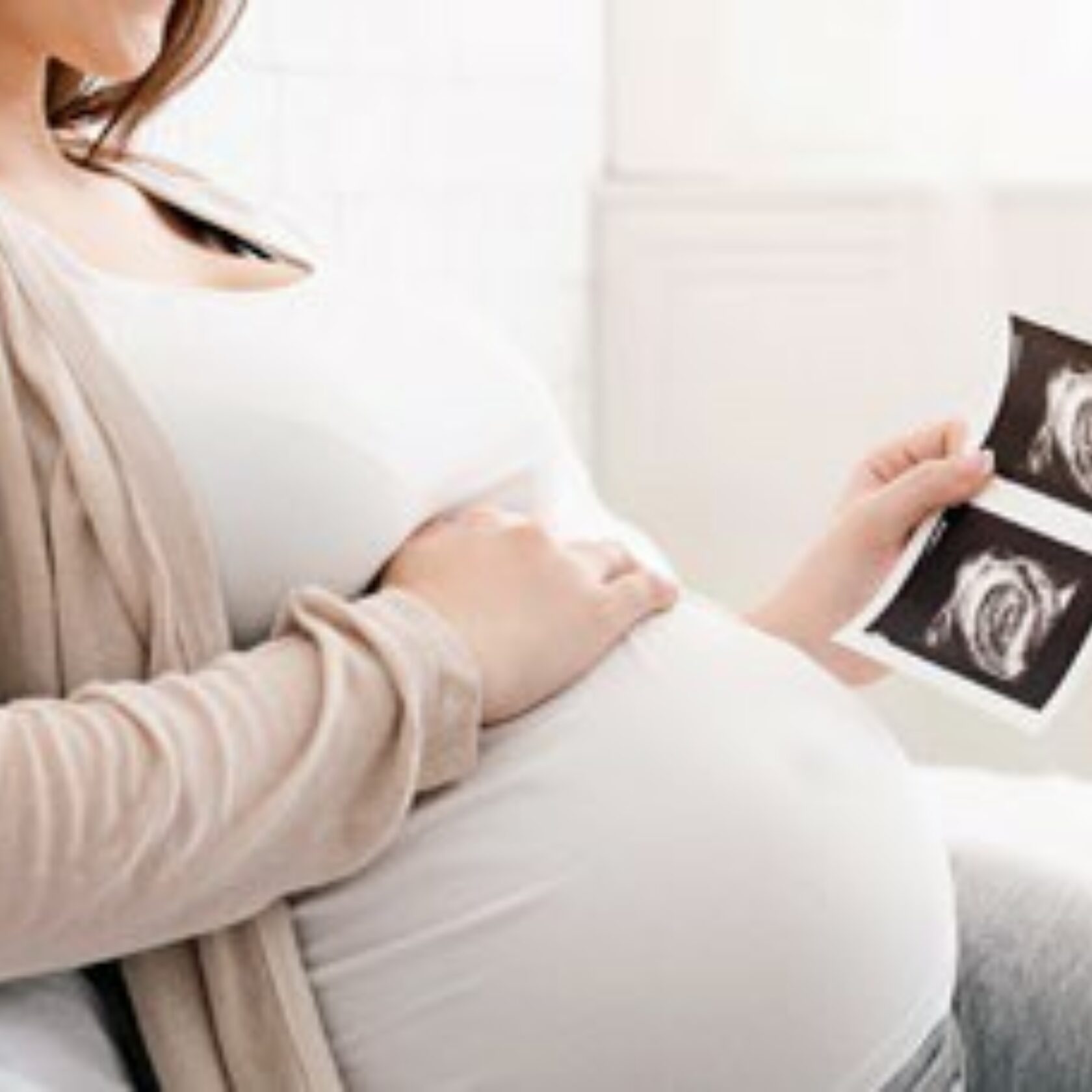 Schwangere Frau blickt auf Ultraschallbilder