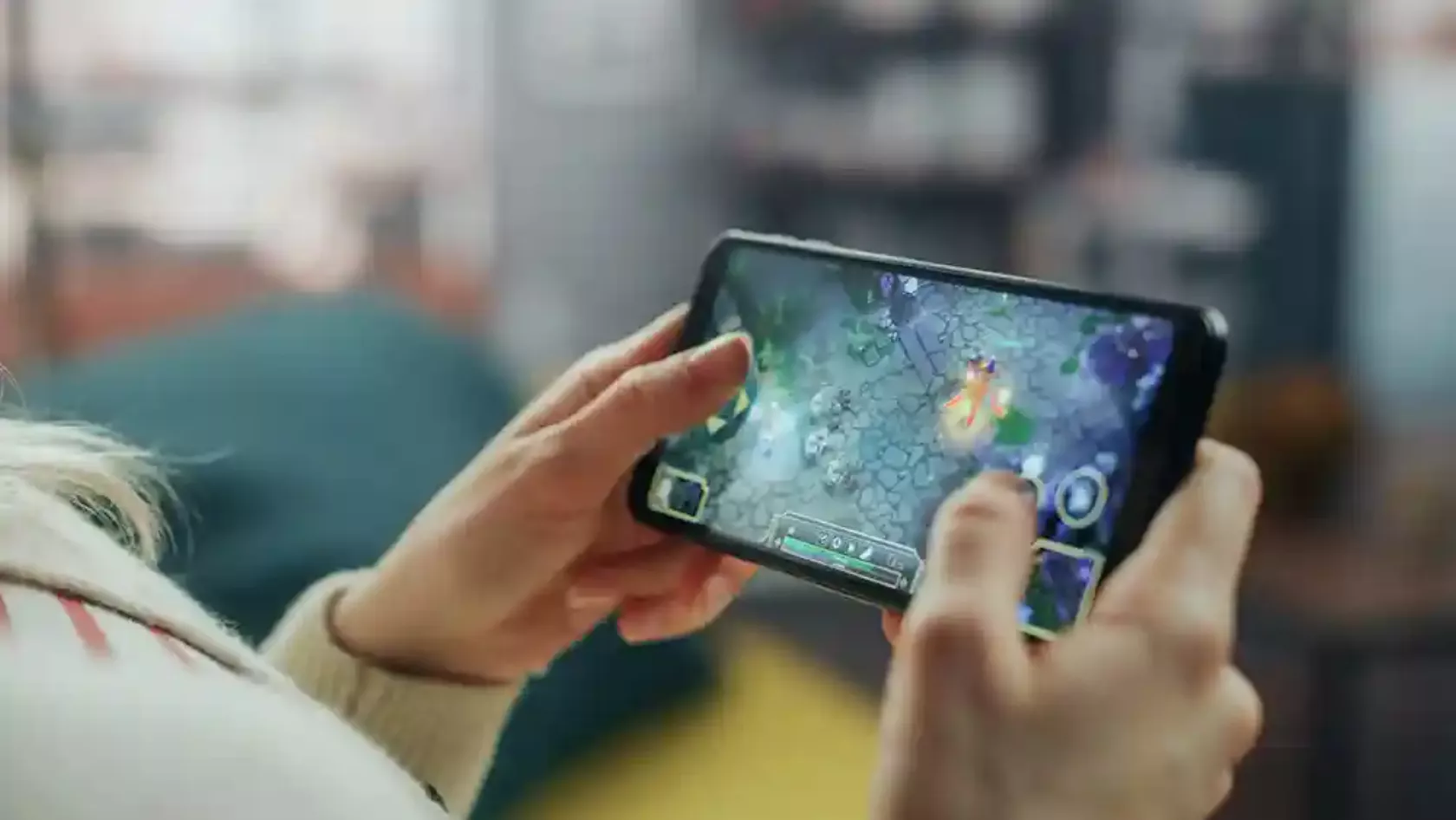 Smartphone, auf dem ein Videospiel läuft, in den Händen einer Person.