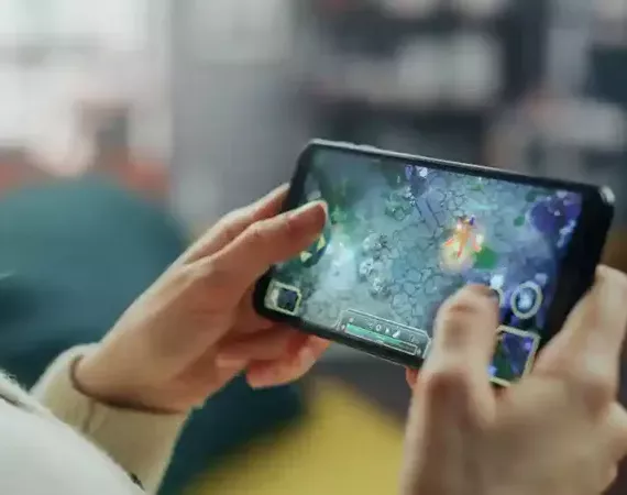 Smartphone, auf dem ein Videospiel läuft, in den Händen einer Person.